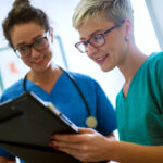 two nurses talking to each other with clipboard