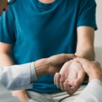 Physical therapist checks the patient wrist by pressing the wris