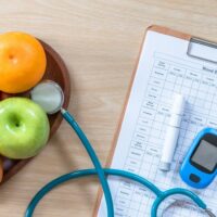 Healthy foods and diabetes management tools, including a glucose meter, on a table.