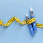 Two blue injection sticks placed on a blue background, showcased next to measuring tape