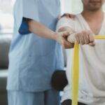 A man with a yellow bandage in hand is comforted by a woman holding his hand, depicting a moment of emotional support.