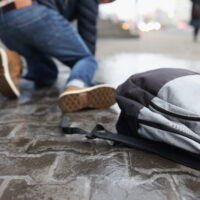 Man with backpack felling on slippery sidewalk in winter closeup. Ice injuries concept